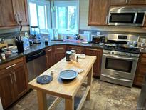 Well-lit kitchen with stainless steel appliances, dark countertops, and wood cabinets at 1207 Joliet St, Aurora, CO 80010