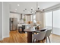 Bright kitchen with stainless steel appliances, center island, and a dining area with hardwood floors at 3361 Yukon Ct, Wheat Ridge, CO 80033