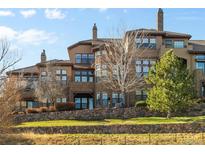 Multi-story home featuring multiple balconies and lots of windows overlooking a green lawn and rock wall at 7882 Vallagio Ln, Englewood, CO 80112