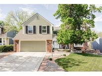 Charming two-story home with a well-manicured lawn, brick accents, and an attached two-car garage at 9867 W Berry Dr, Littleton, CO 80123