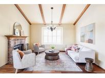 Bright living room with hardwood floors, fireplace, wood beams, and ample seating at 9867 W Berry Dr, Littleton, CO 80123