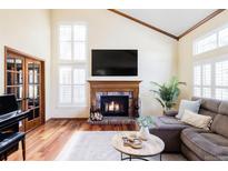 Inviting living room with a cozy fireplace, high ceilings, natural light and wood flooring at 9867 W Berry Dr, Littleton, CO 80123