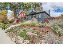 Landscaped front yard with rocks and plants leading to a charming blue house at 1538 Albion St, Denver, CO 80220