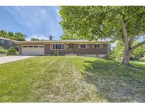 Charming brick home featuring an attached garage and a well-maintained lawn at 1701 S Valentine Way, Lakewood, CO 80228