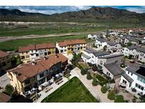 Stunning aerial view of a neighborhood with mountain backdrop showcasing well-maintained homes and green spaces at 15576 W Washburn Cir, Lakewood, CO 80228