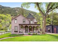 Charming two-story home with a covered porch and a well-manicured lawn against a mountain backdrop at 715 Main St, Georgetown, CO 80444