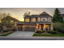 Charming two-story home with a stone facade, inviting front porch, and lush landscaping at sunset at 4307 Lilly Gulch Trl, Castle Rock, CO 80109