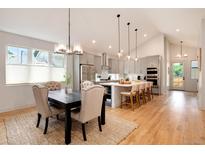 Open kitchen and dining area boasts stainless appliances, a large island, and hardwood floors at 4711 S Logan St, Englewood, CO 80113