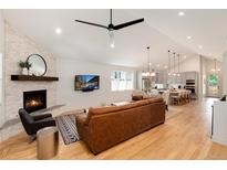 Open-concept living room boasts stone fireplace, hardwood floors and flows into the kitchen at 4711 S Logan St, Englewood, CO 80113