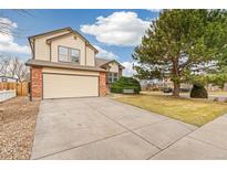 Charming two-story home featuring a two-car garage, brick accents, and a well-maintained front yard with mature tree at 10663 Dexter Dr, Thornton, CO 80233