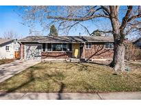 Charming brick home featuring a well-maintained front yard with mature tree and a welcoming yellow front door at 1324 S Niagara St, Denver, CO 80224