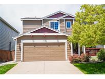 Inviting two-story home showcasing a well-maintained lawn, charming front porch, and a convenient two-car garage at 9927 Aftonwood St, Highlands Ranch, CO 80126