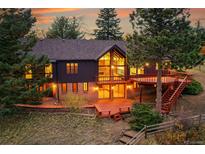 Stunning exterior with large deck, windows, and beautiful trees, offering a serene and private setting at 21849 Cabrini Blvd, Golden, CO 80401