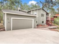 Charming gray two-story home with a two-car garage and a red staircase leading to the front deck at 510 Silhouette Way, Monument, CO 80132