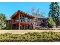 Stunning two-story home featuring a balcony with a beautiful wood finish and lush landscaping at 40 Charlou Cir, Cherry Hills Village, CO 80111