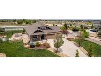 Charming two-story home with a well-manicured lawn, landscaped garden beds, and long driveway at 10653 E 163Rd Ct, Brighton, CO 80602