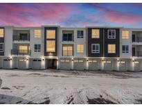 Modern two-story townhome building with attached garages and snow-covered parking lot at 6153 N Ceylon St # 201, Denver, CO 80249