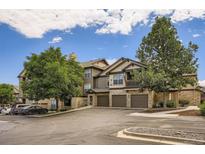View of a modern, multi-story condo building with stone accents and attached garages under a blue sky at 7493 S Quail Cir # 928, Littleton, CO 80127