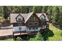 Stunning log home featuring a spacious deck perfect for entertaining and enjoying the surrounding mountain views at 13525 Woodmoor West Dr, Larkspur, CO 80118