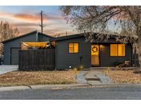 Charming home featuring a dark exterior, inviting front yard, and cozy outdoor lighting, perfect for evening enjoyment at 8120 W 54Th Pl, Arvada, CO 80002