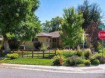 Charming home featuring a well-kept lawn, a rustic wood fence, and a beautifully landscaped garden at 1594 S Locust St, Denver, CO 80224