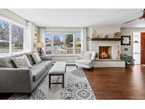 Bright living room features a fireplace, large window, and hardwood floors at 1594 S Locust St, Denver, CO 80224
