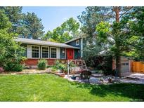 Charming home featuring a red door, brick accents, a swing, and lush landscaping at 6360 S Kendall St, Littleton, CO 80123