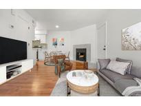 Bright living room featuring a fireplace, hardwood floors, and an open layout to the dining area and modern kitchen at 1830 Newland Ct # 319, Lakewood, CO 80214