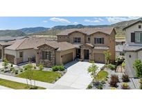 Two-story stucco home with tile roof, attached garage, concrete driveway and mountain views at 2125 S Orion St, Lakewood, CO 80228