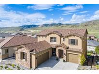 Beautiful two-story home with a three car garage and a stone archway entrance; mountain views can be seen in the background at 2125 S Orion St, Lakewood, CO 80228