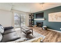 Cozy living room with fireplace, TV, and sliding door to balcony at 3141 S Tamarac Dr # 202E, Denver, CO 80231