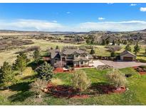 Expansive aerial view of home, well manicured lawn and landscaping, large trees, and beautiful mountain views at 3891 Windchant Cir, Castle Rock, CO 80104