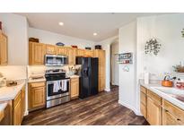 Bright kitchen features stainless steel appliances, wooden cabinets, and wood-look flooring at 8976 Fox Dr # 101, Thornton, CO 80260