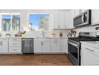 Bright kitchen features white cabinets, stainless steel appliances, hardwood floors, and natural light at 7856 W 43Rd Pl, Wheat Ridge, CO 80033