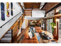 Spacious living room featuring exposed wood beams, an open staircase, and comfortable seating at 3033 Blake St # 109, Denver, CO 80205