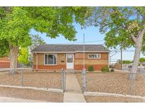 Charming single-story brick home featuring a well-kept front yard and a secure chain-link fence at 6930 Warren Dr, Denver, CO 80221