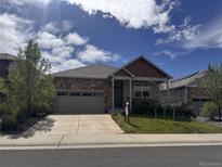 Charming single-Gathering home featuring a brick facade, well-manicured lawn, and a two-car garage at 5741 Echo Park Cir, Castle Rock, CO 80104