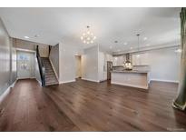 Bright living room featuring hardwood floors, staircase, and open access to a modern kitchen at 12255 Hazel Spruce Ct, Parker, CO 80134