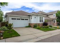 Charming home with an attached garage, stone accents, a well-manicured lawn, and beautiful landscaping at 10581 Pearlwood Cir, Highlands Ranch, CO 80126