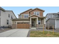 Inviting two-story home with a charming front porch, a well-manicured lawn, and an attached two-car garage at 5601 Inland Ave, Firestone, CO 80504