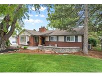 Charming brick home featuring a lush lawn, mature trees, and well-maintained landscaping at 32 Skyline Dr, Wheat Ridge, CO 80215