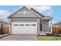 Charming home featuring a large garage door and a welcoming front entrance under a covered porch at 9463 Yampa Ct, Commerce City, CO 80022