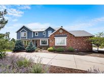 Charming two-story home with a combination of blue siding and brick, complemented by a well-manicured lawn and a long driveway at 19052 E Briarwood Dr, Centennial, CO 80016