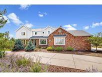 Charming brick and siding home with manicured landscaping and mature trees under a sunny sky at 19052 E Briarwood Dr, Centennial, CO 80016