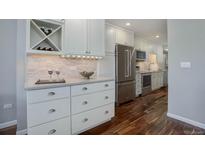 Bright kitchen featuring custom white cabinets, a wine rack, stainless steel appliances, and hardwood floors at 909 N Logan St # 1B, Denver, CO 80203