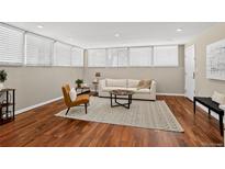 Cozy living room featuring wood floors, neutral walls, and natural light from large windows with white blinds at 909 N Logan St # 1B, Denver, CO 80203