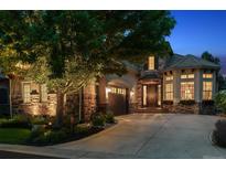 Charming home with a stone and stucco exterior, well-manicured landscaping, and an attached garage at dusk at 35 Brookhaven Pl, Littleton, CO 80123