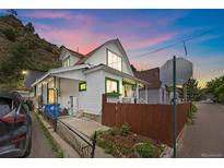 Charming two-story home with white siding, green trim, and a quaint front yard with mountain views at 902 Virginia St, Idaho Springs, CO 80452