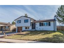 Charming two-story home with white painted brick, updated black trim, and attached garage on a sunny lot at 4328 S Carr Ct, Littleton, CO 80123
