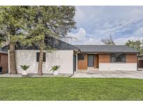 Charming home with a manicured lawn, trees, and updated exterior featuring light colored brick and modern design accents at 920 S Hudson St, Denver, CO 80246
